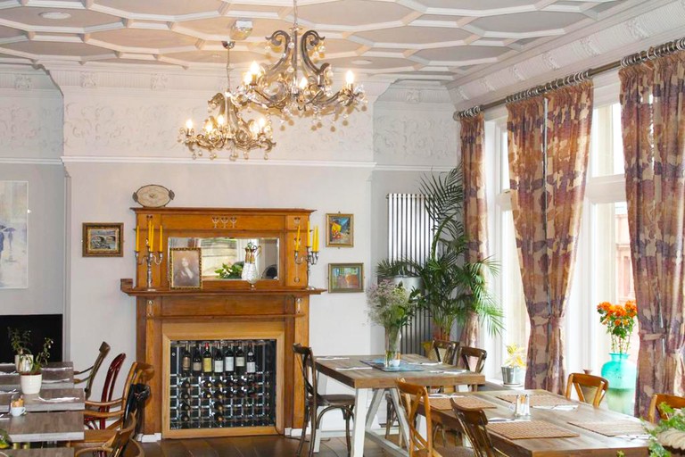 The inviting dining room at the Bentinck Hotel with mismatched chairs, framed art and a fireplace-turned-wine holder