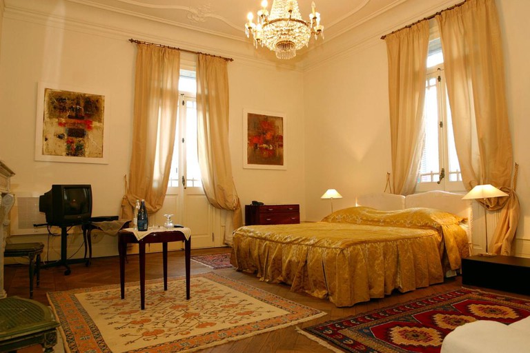 High-ceilinged room at La Maison de Sophie, with a trio of rugs, a chandelier and a large bed
