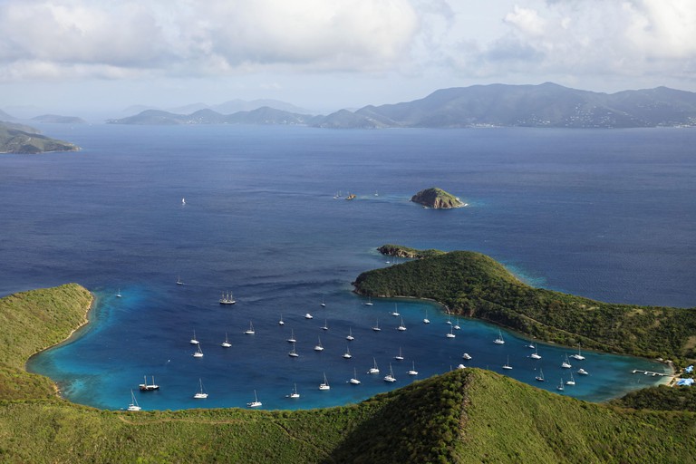 Aerial view of the Bight, Norman Island Bay, with lots of boats dotting the bay and Tortola Island in the background